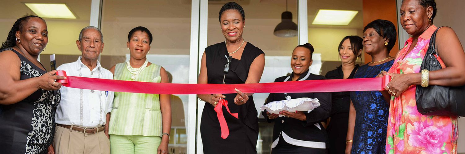 A group of people gather for a ribbon cutting ceremony at a business opening event.