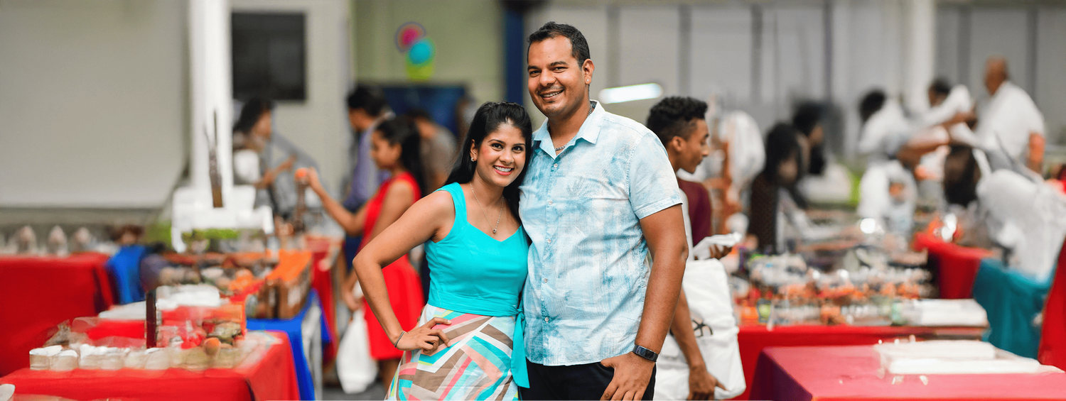 Couple in blue and turquoise attire enjoying a festive gathering with red tablecloths and decorations.