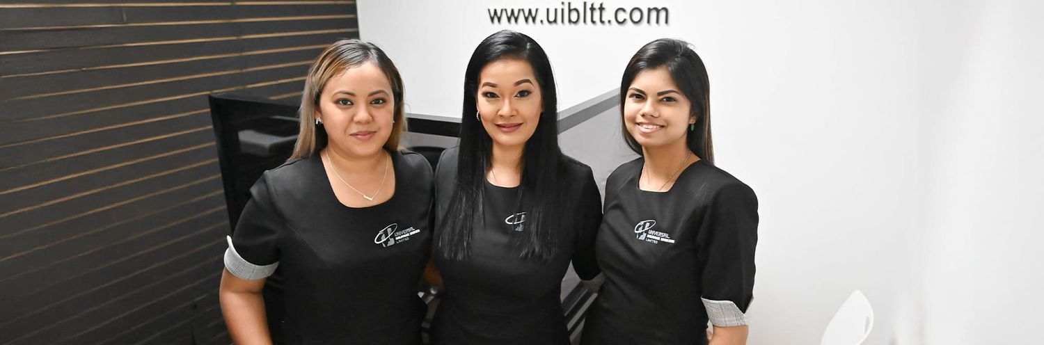 Three team members wearing matching black uniforms smile together in a professional office setting.