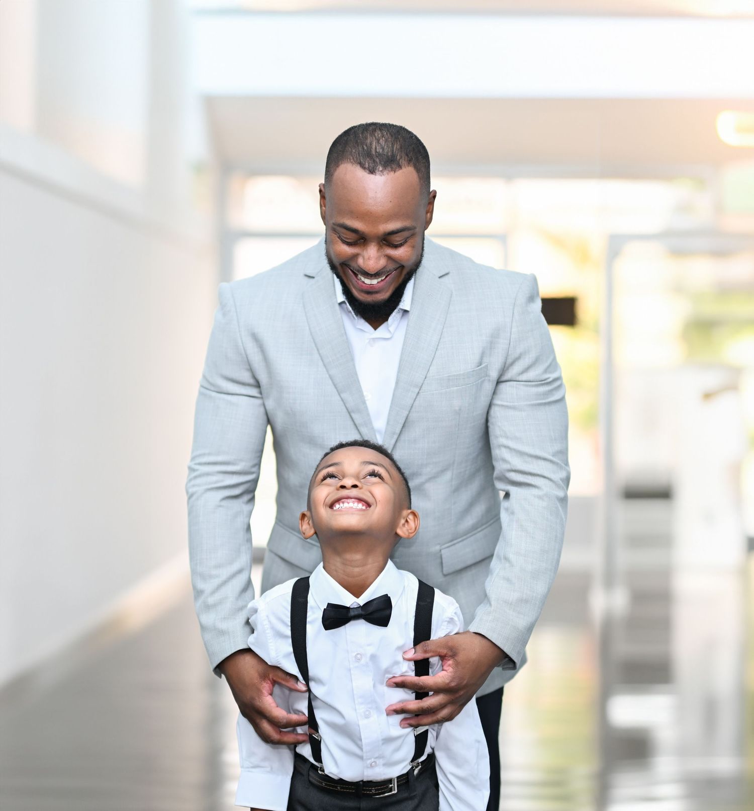 Joyful formal portrait in bright hallway setting showing genuine happiness.