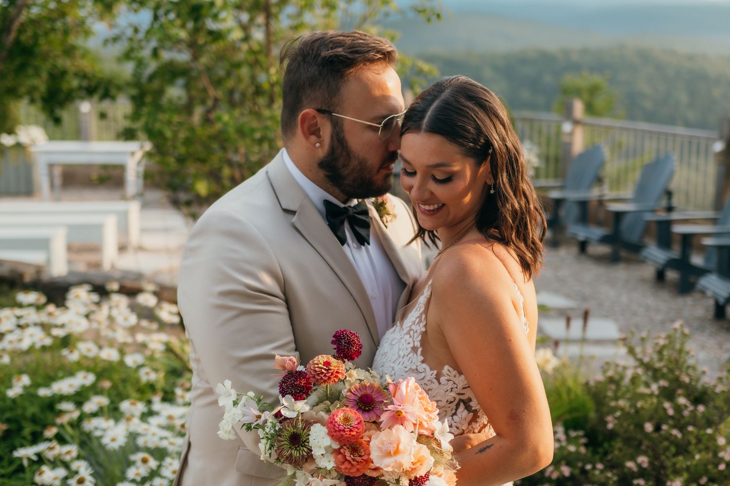 A bride and groom posing outside with a beautiful bouquet