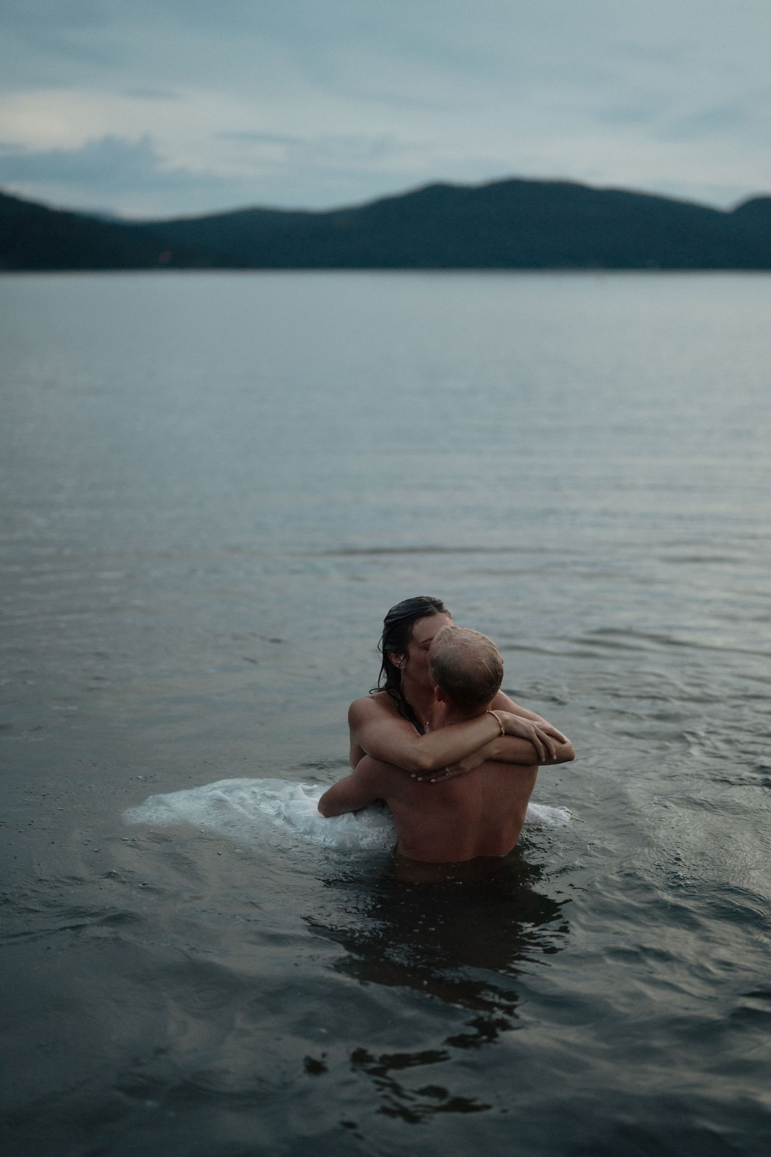 Bride and groom kissing in lake in Montana after jumping in after their wedding reception