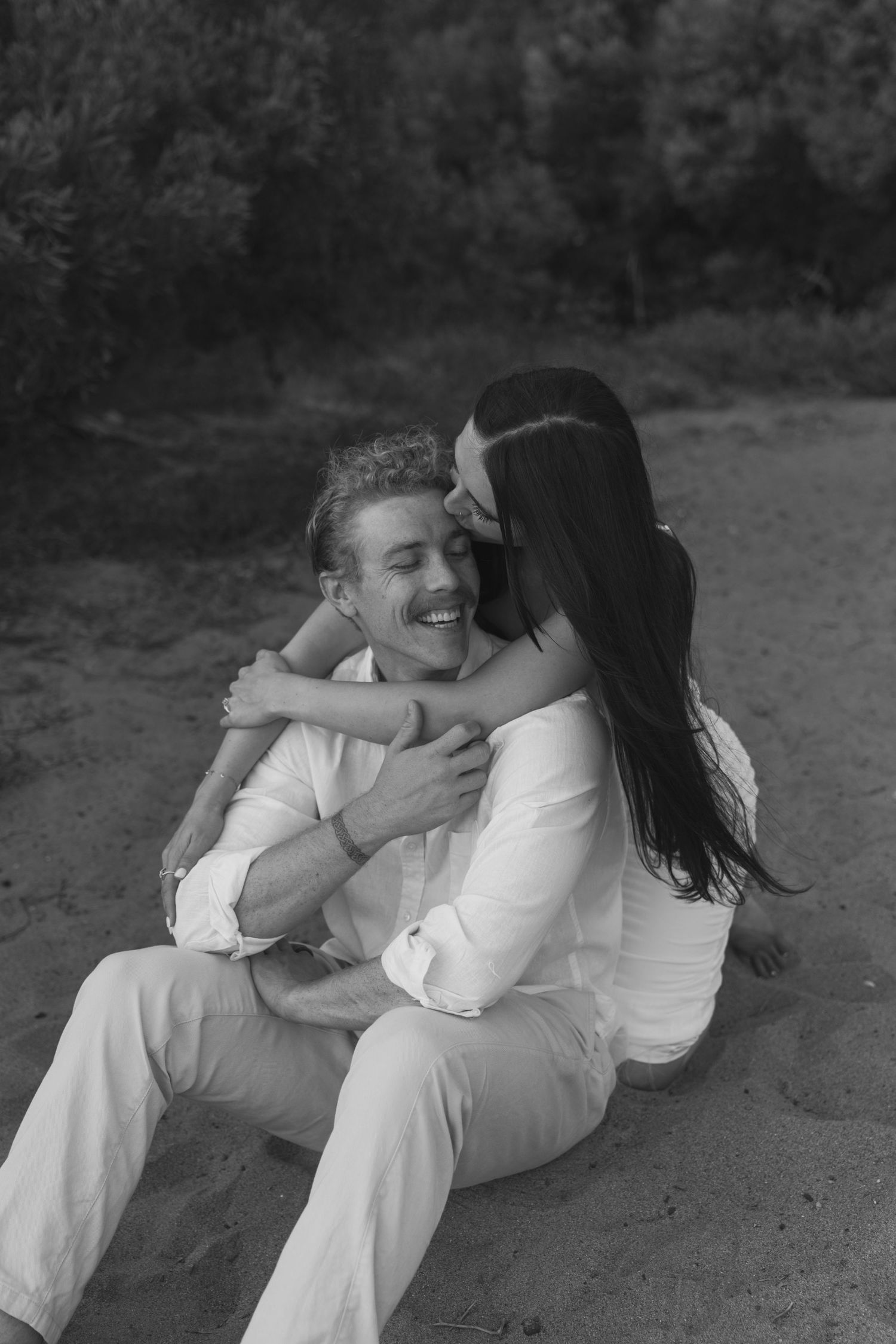 Couple laughing and kissing on the cheek in Laguna beach