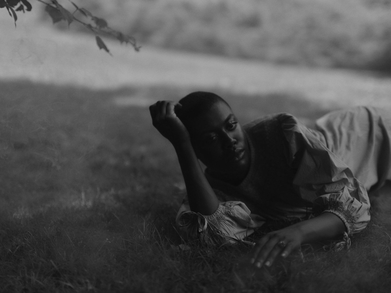 A person lies peacefully in grass while resting outdoors in black and white vintage photograph.