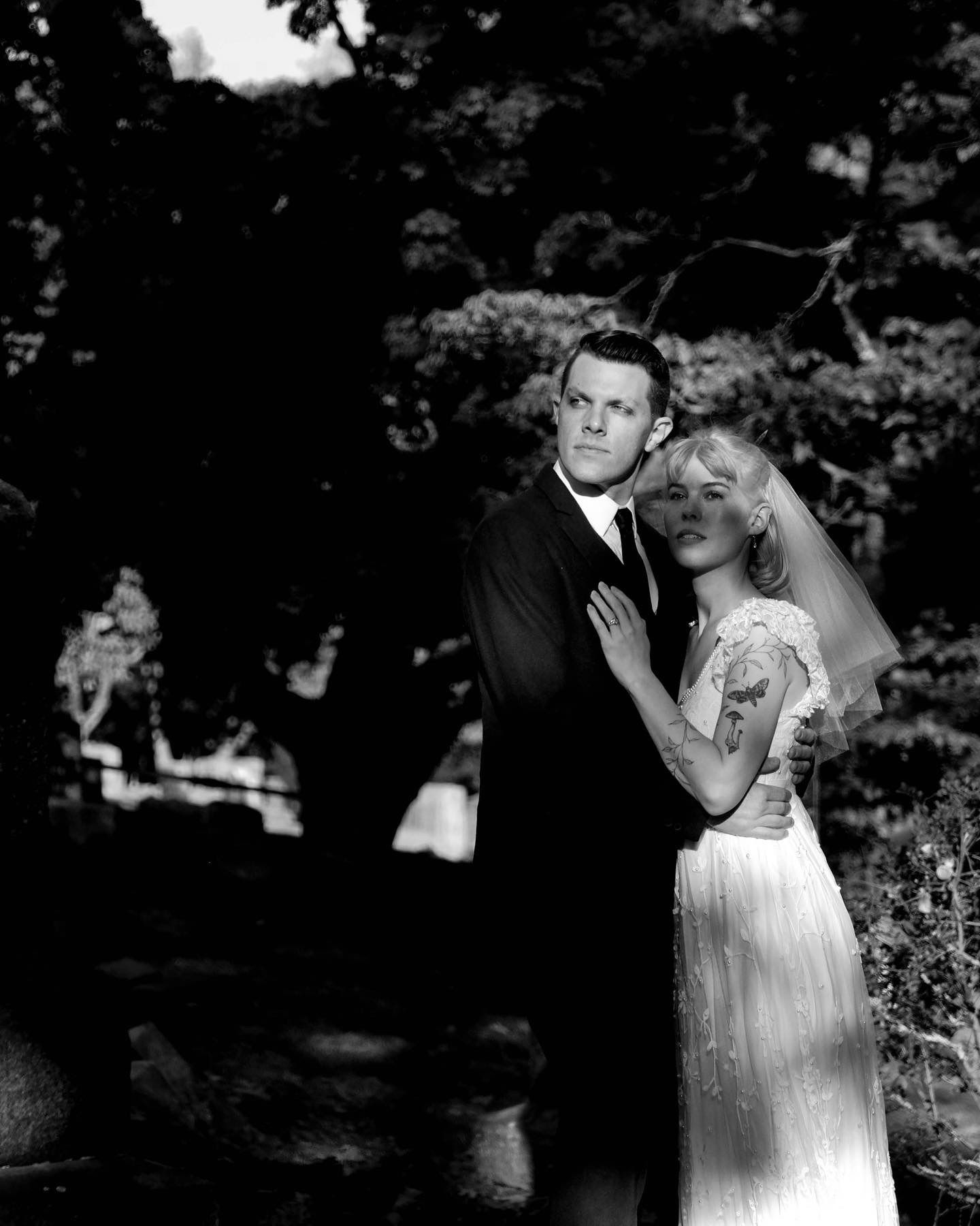 A vintage black and white photograph captures a romantic moment between a couple in formal attire.