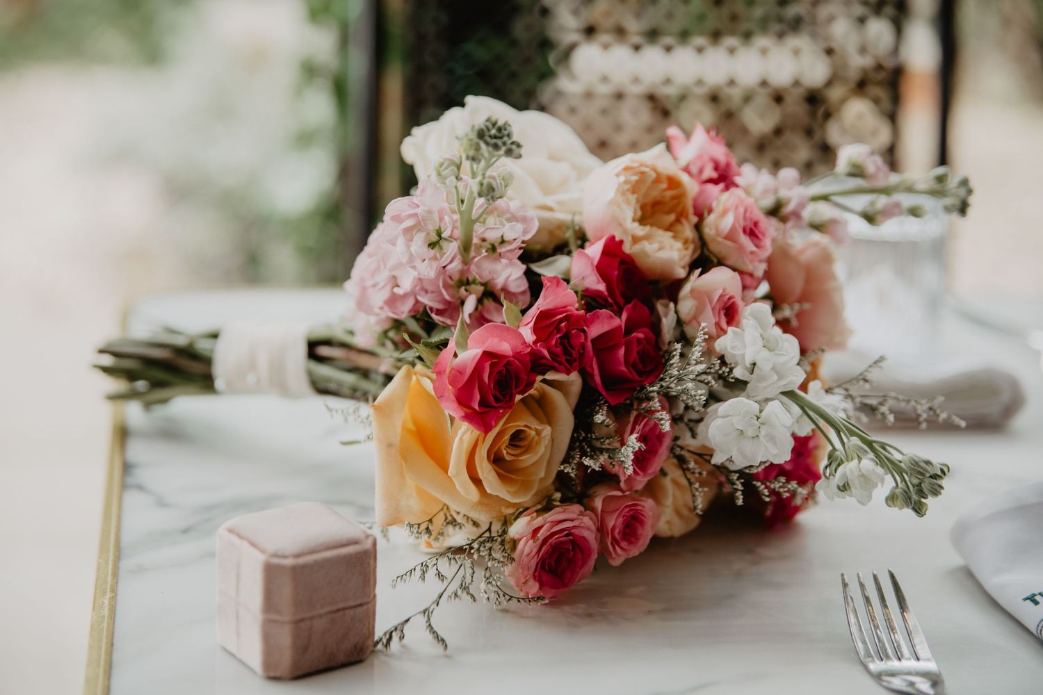 Elegant table setting with pink and coral floral arrangements for a wedding reception.