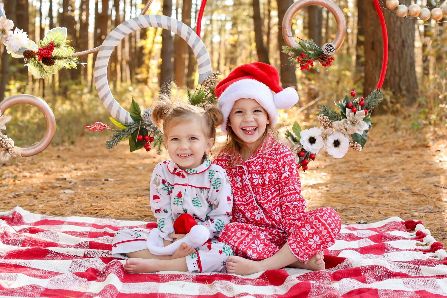 Holiday portrait on red blanket with Christmas decorations hanging in forest background.