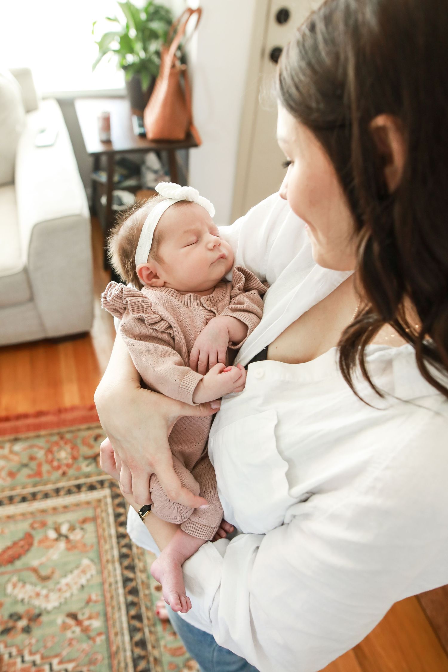 Tender moment between parent and newborn baby in living room with patterned rug.