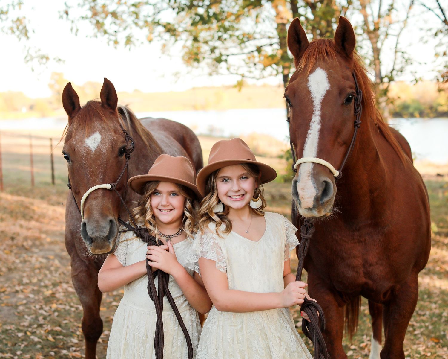 Children posing with brown horses in a rustic outdoor setting wearing matching dresses.
