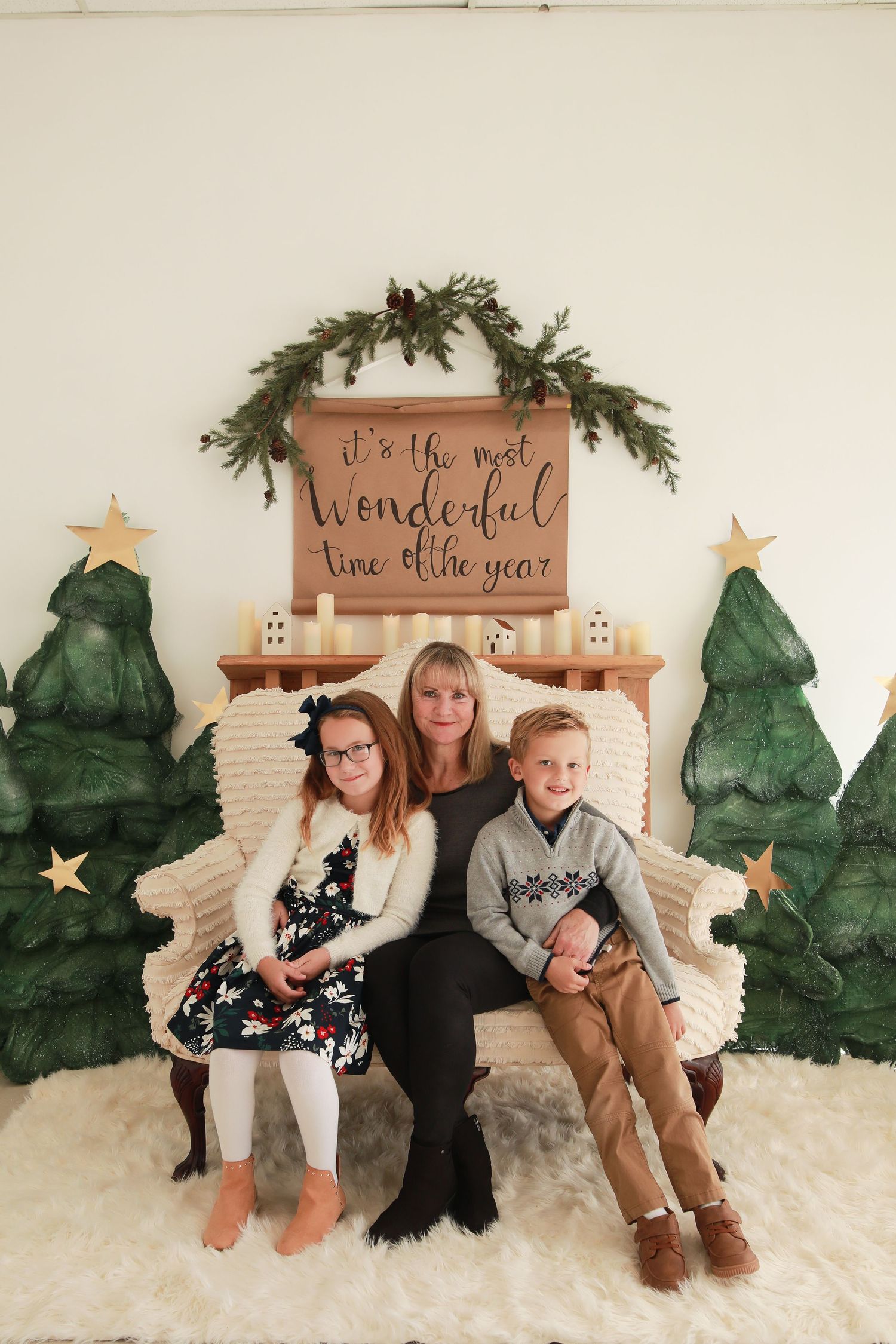 Christmas photo setup with painted evergreen trees and wooden signs against white background.