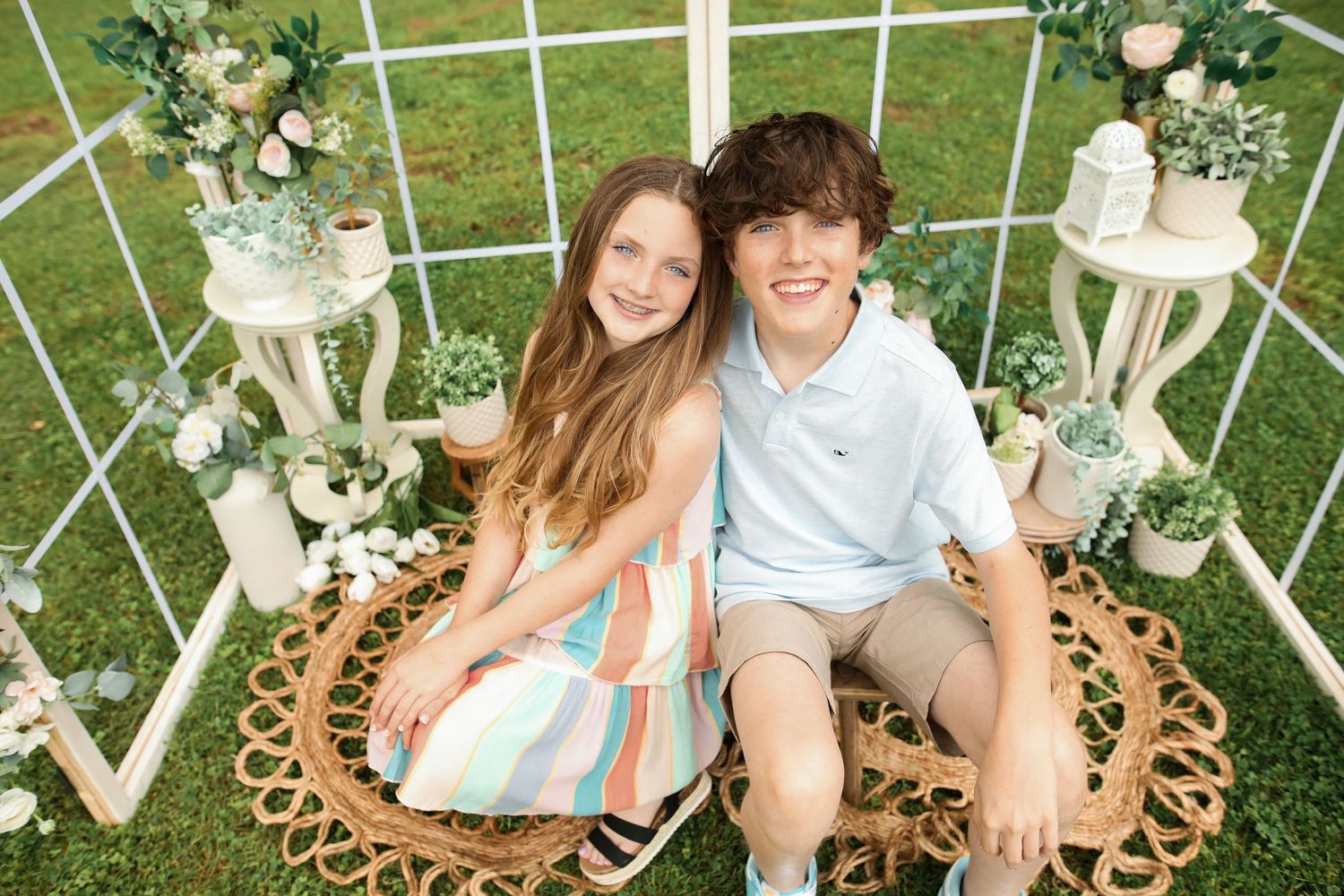 Outdoor photography setup with white lattice backdrop and floral decorations.