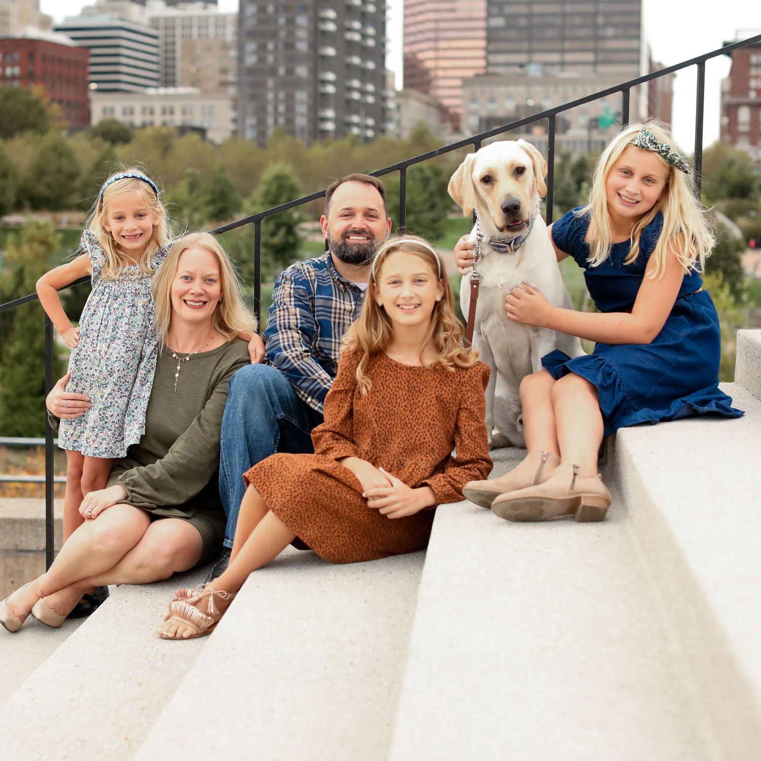 Family lounging together on white outdoor surface with pet dog.