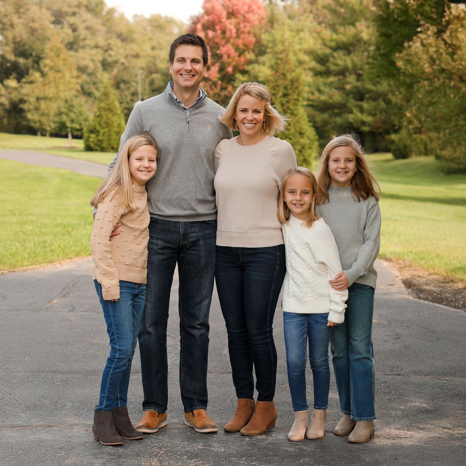 Family members' legs lined up in casual poses on outdoor path during fall season.