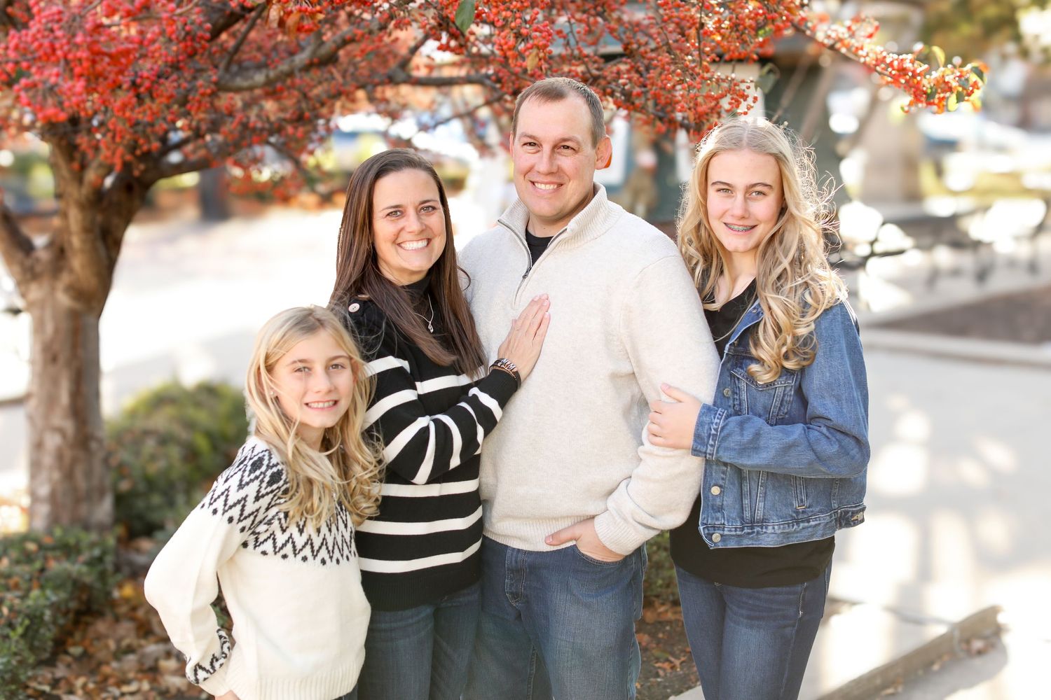 A group stands together under a red autumn tree on a bright day.