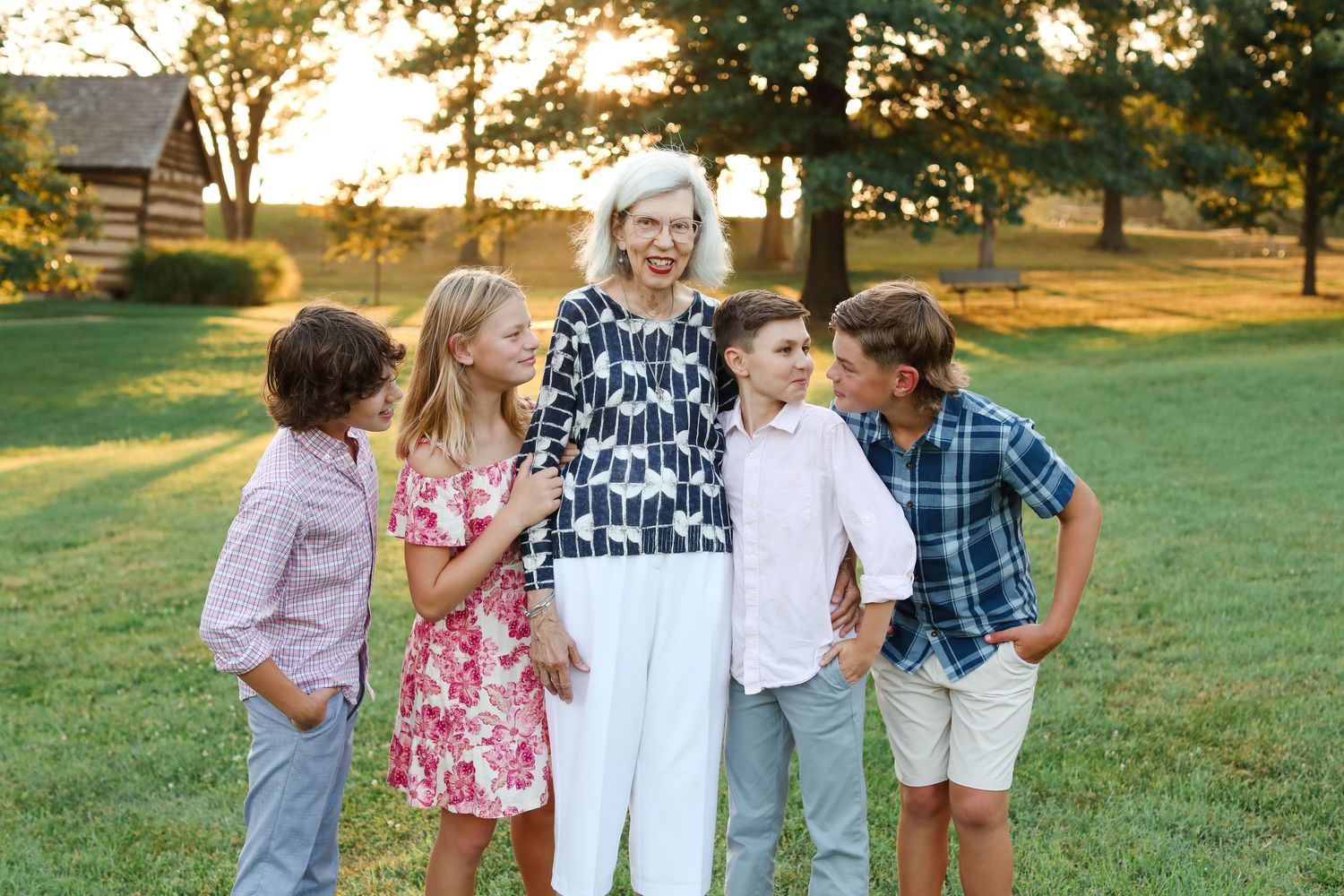 Group portrait in a grassy field during golden hour with coordinated summer outfits.