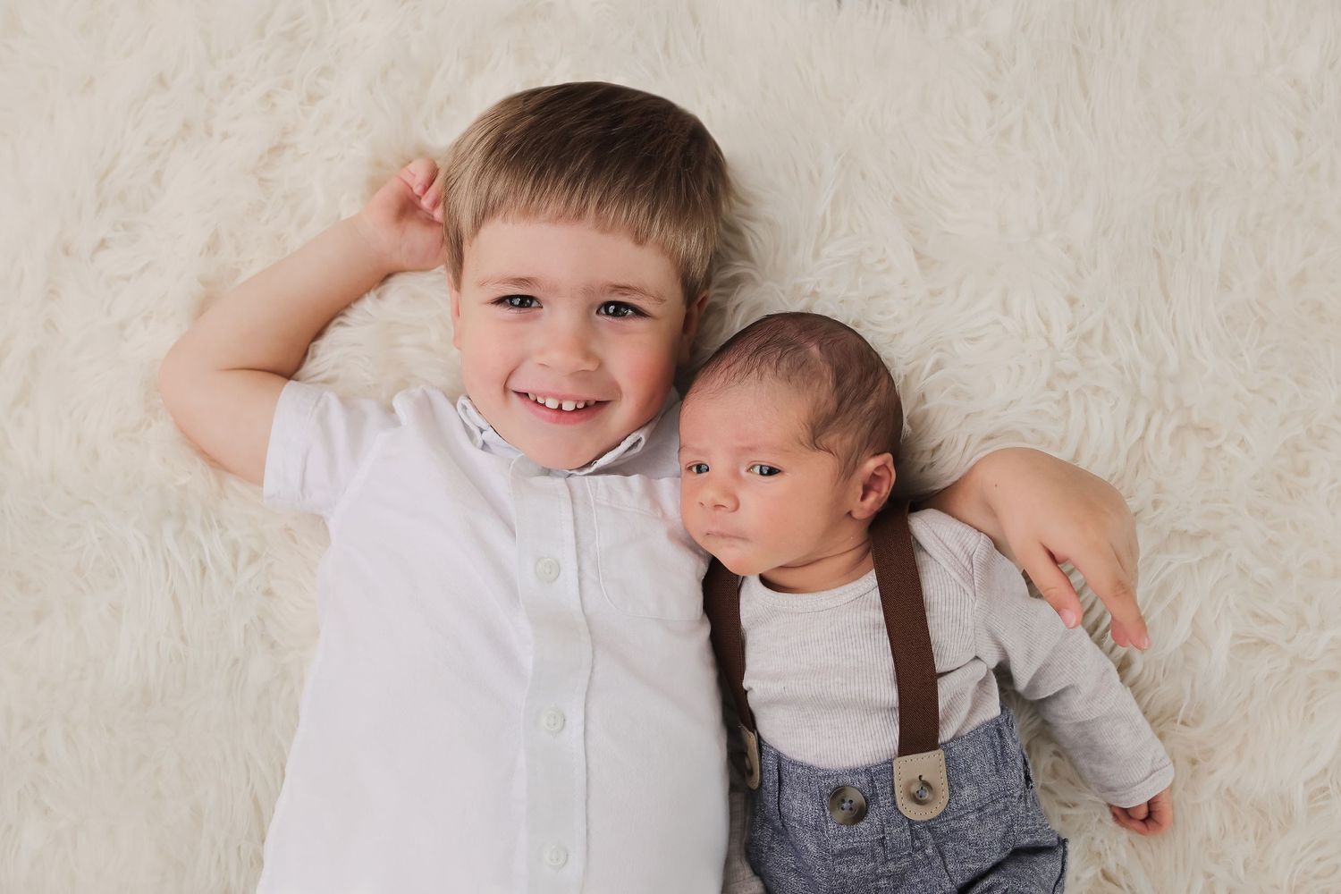Children lying on cream colored carpet during sibling photo session.