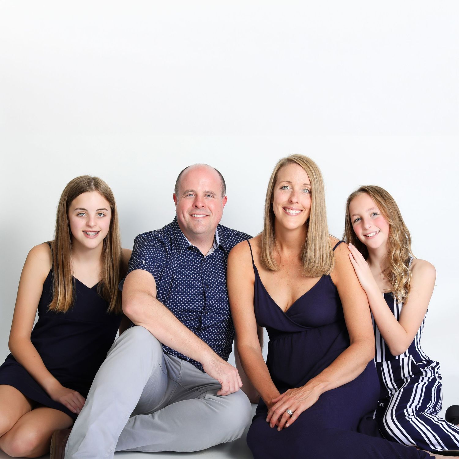 Studio portrait of family wearing coordinated navy blue outfits against white background.