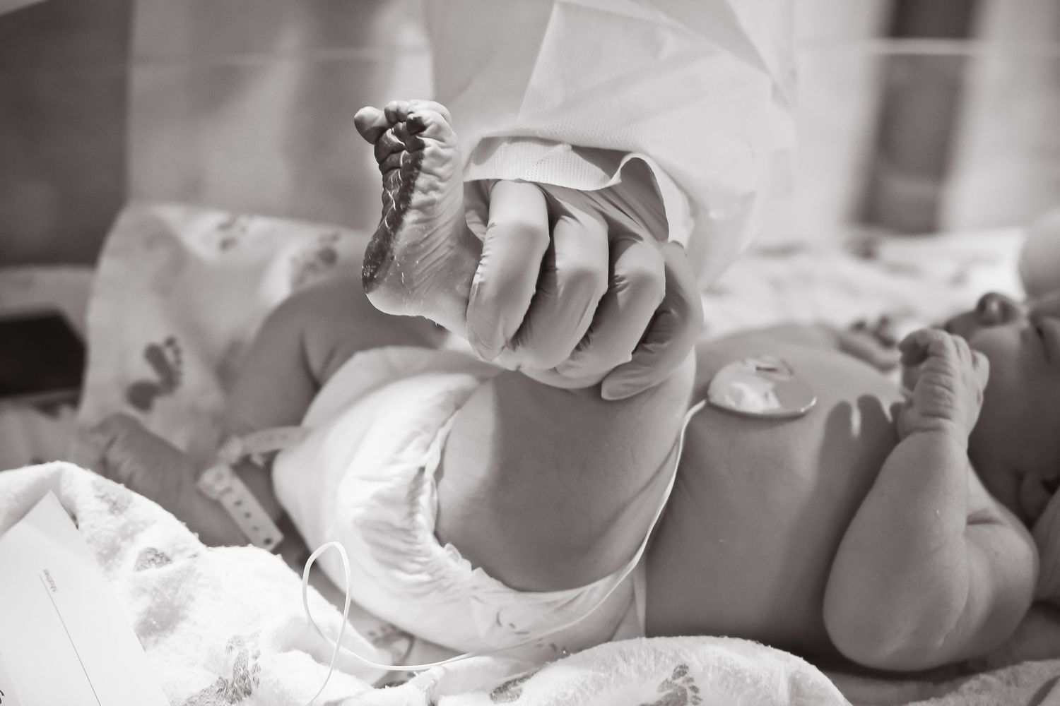 Black and white image of tiny newborn foot being examined.