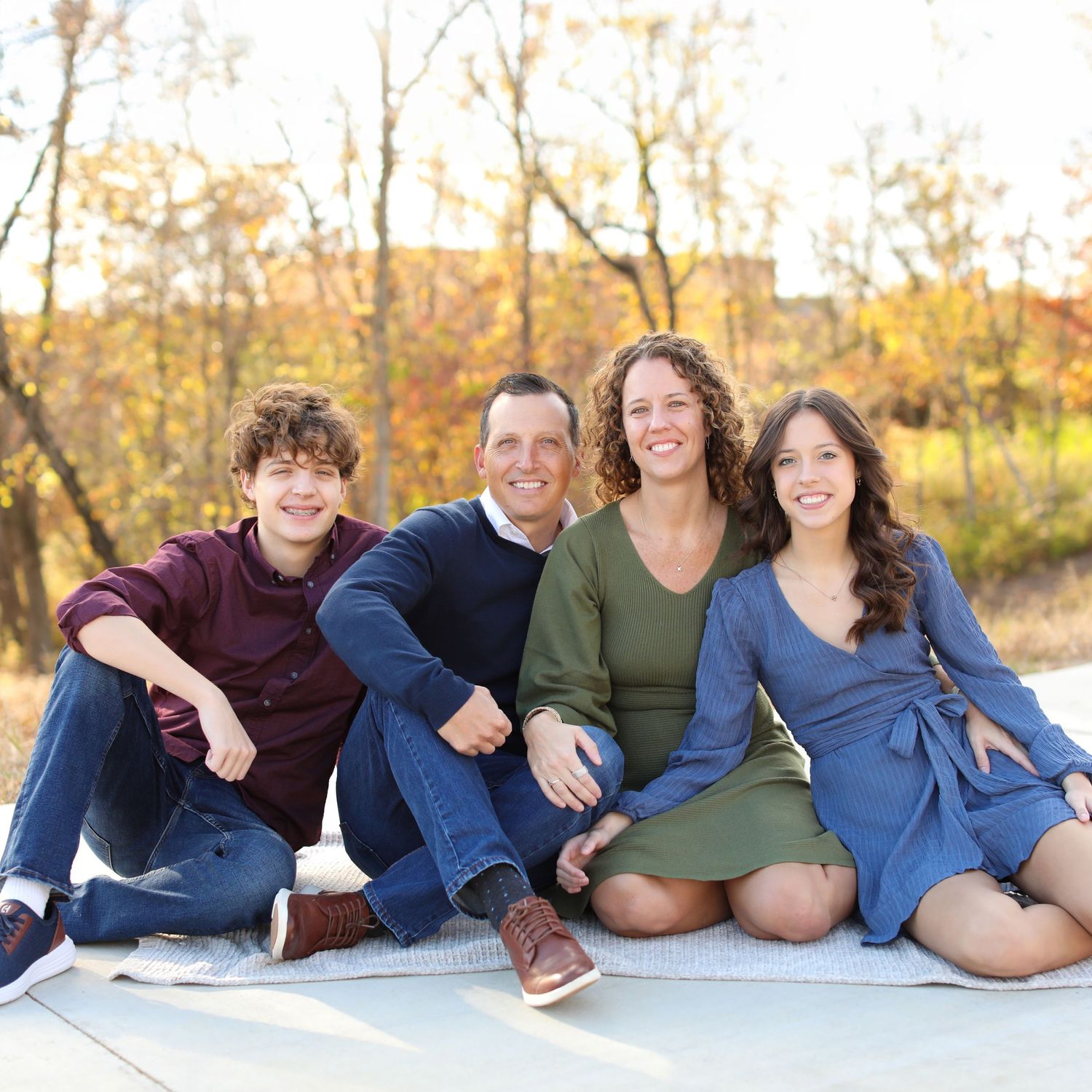 Casual family photo with members lying down in relaxed poses wearing coordinated blue outfits.