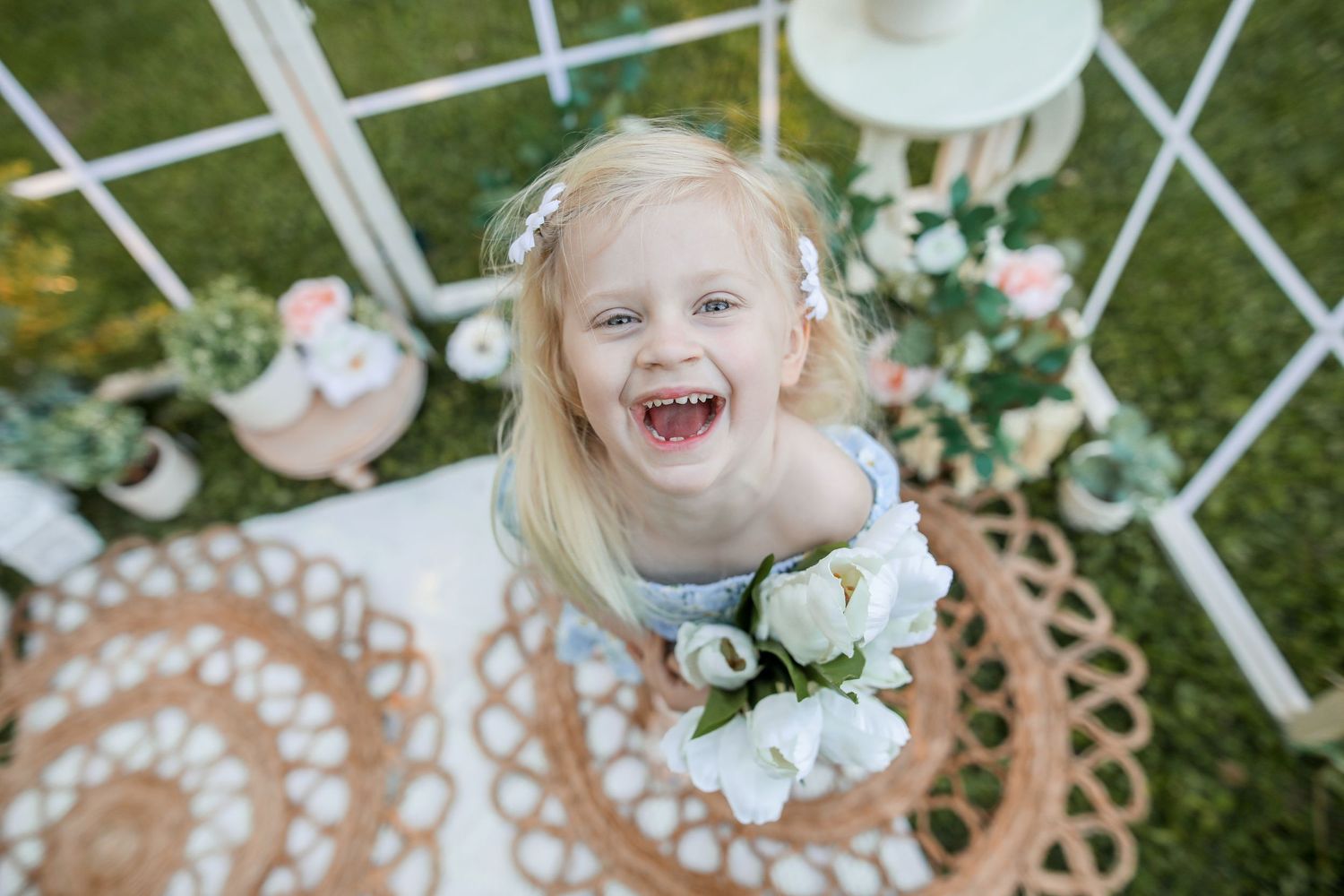 Joyful spring outdoor photo setup with white lattice and floral arrangements.