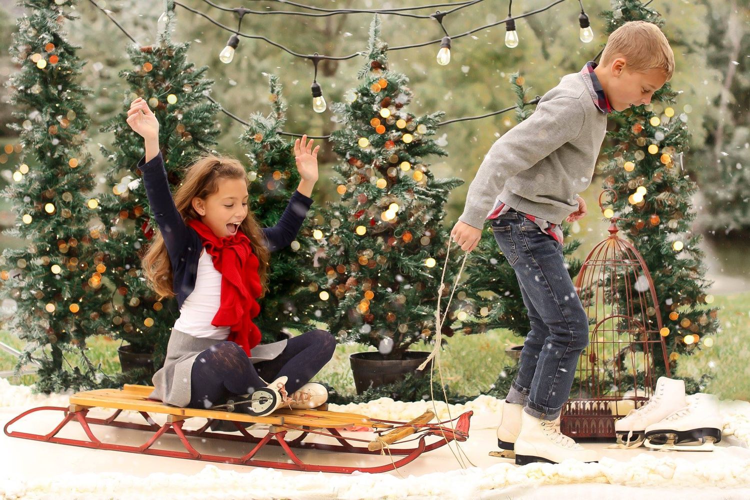 Children playing and having fun on red sled among decorated Christmas trees.