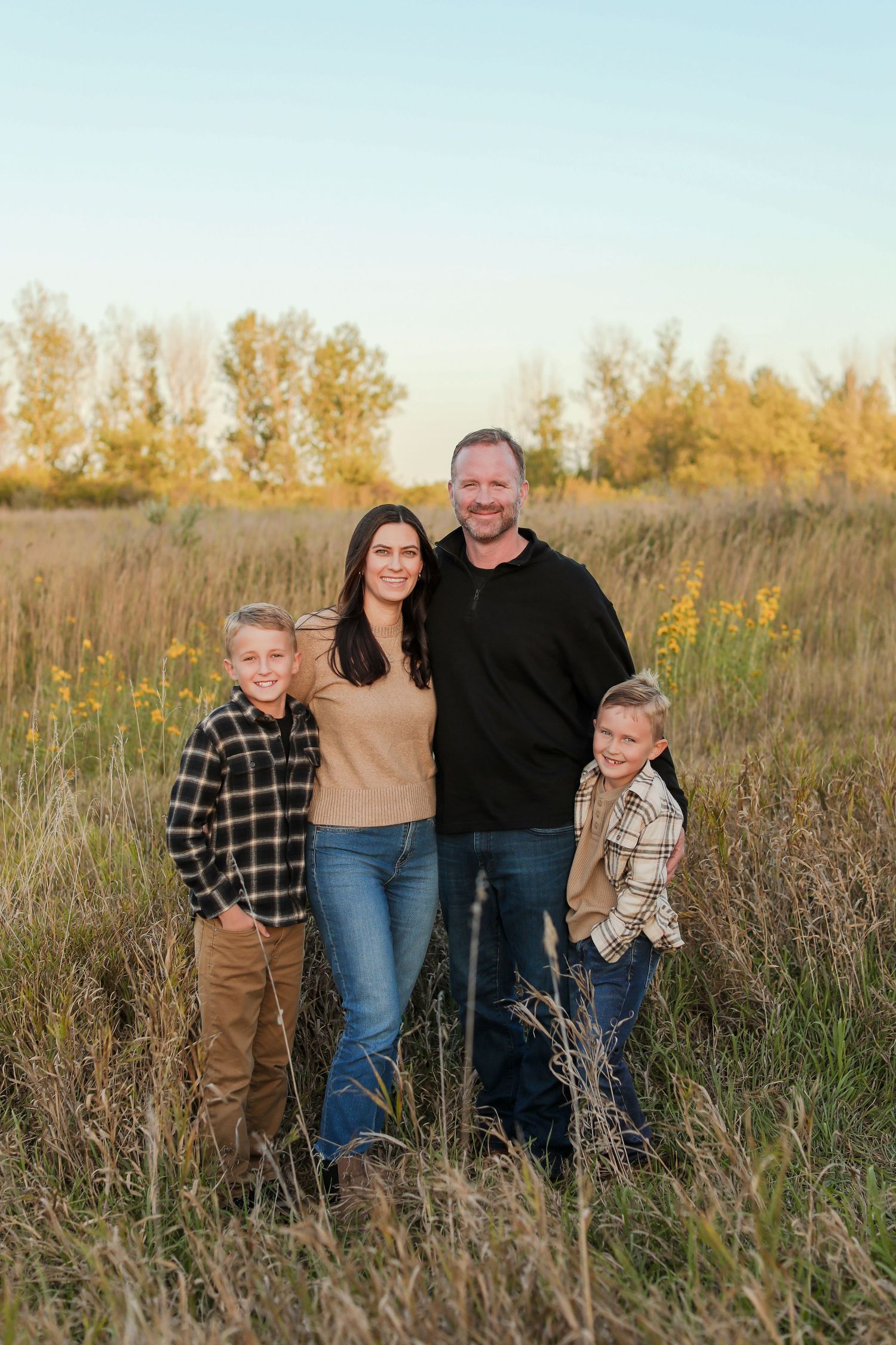 A group poses together in a golden prairie field at sunset.