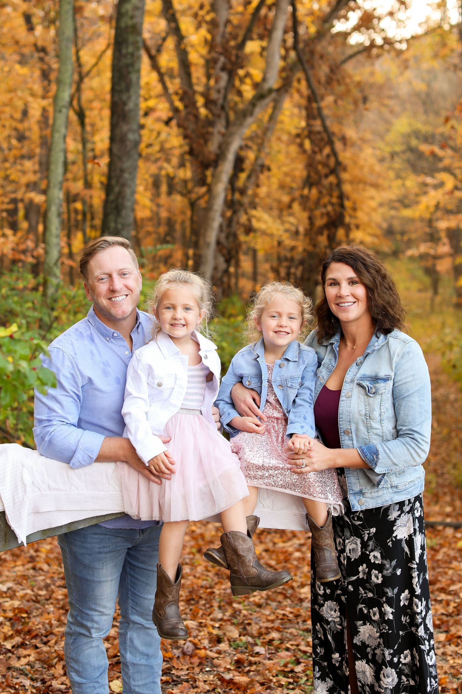 A group poses among fallen autumn leaves in a wooded setting.