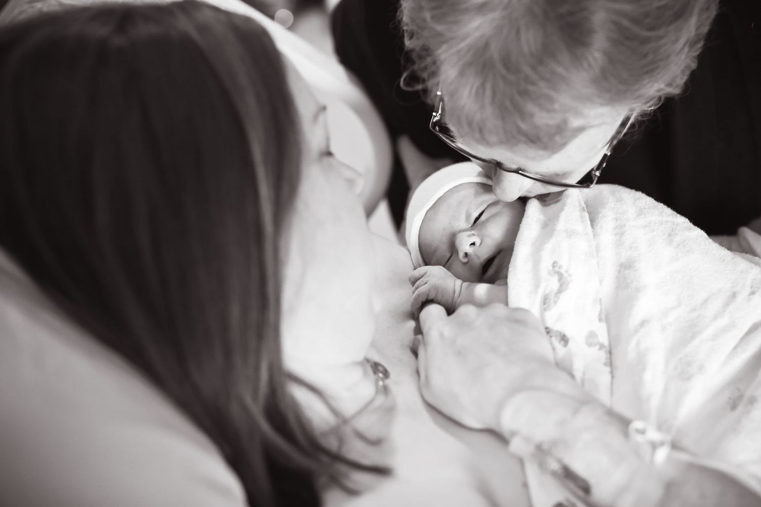 Tender moment with newborn during checkup in black and white.