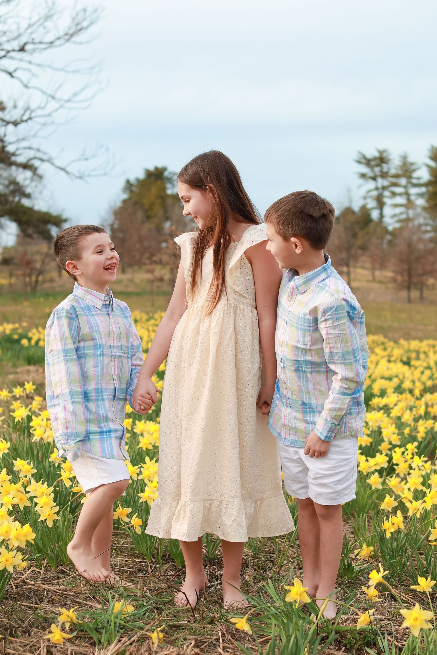 Children playing in a field of blooming yellow daffodils on a spring day.
