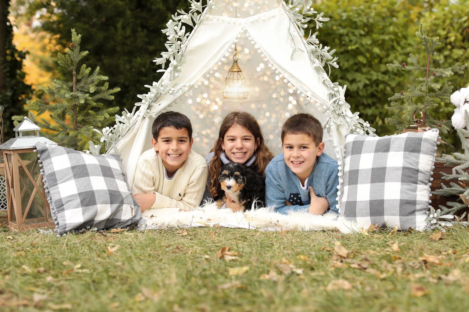 Outdoor family photo session setup with white tent and buffalo plaid blankets against autumn trees.