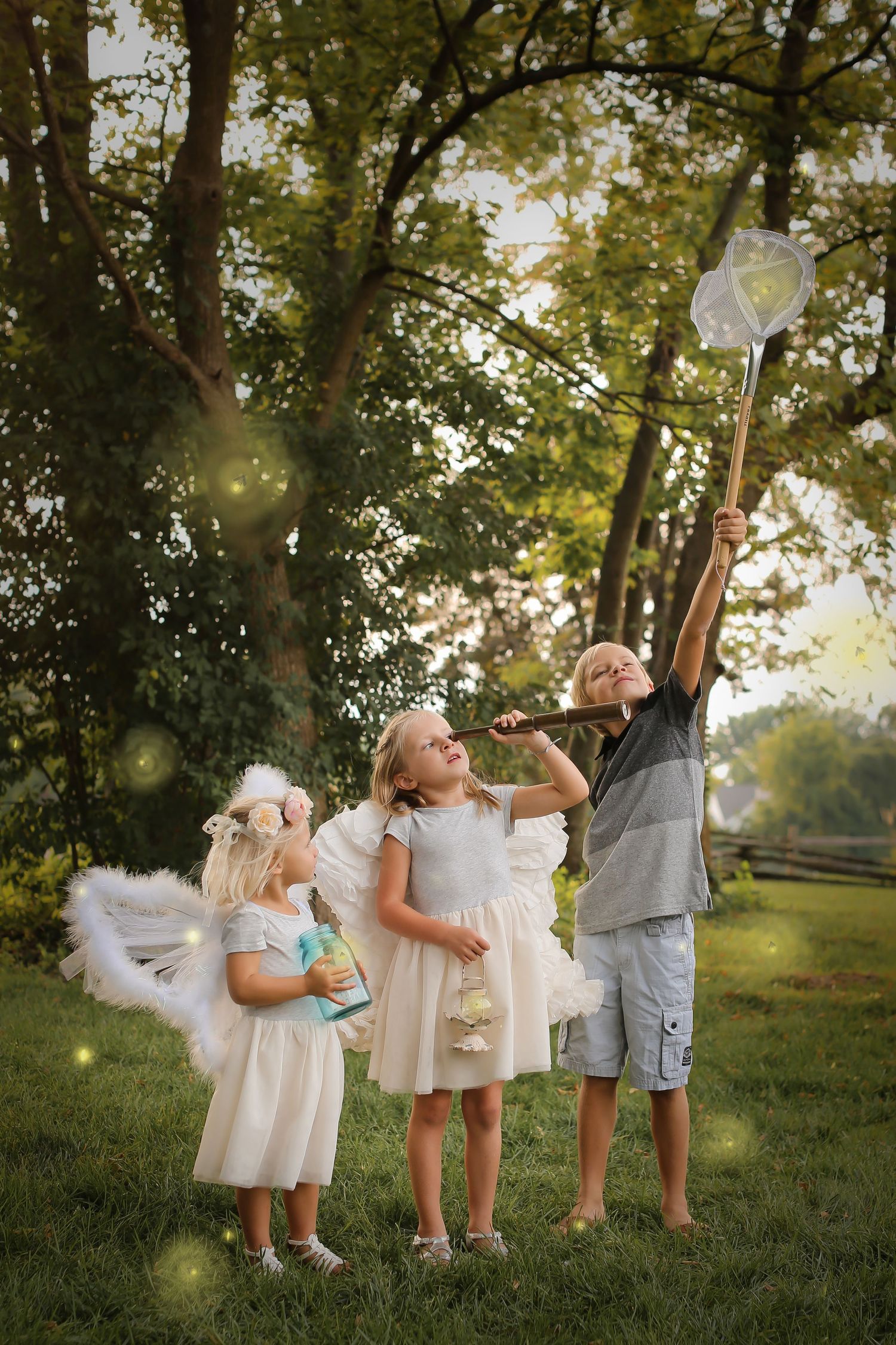 Children in white dresses reaching for butterfly nets in sunlit garden.