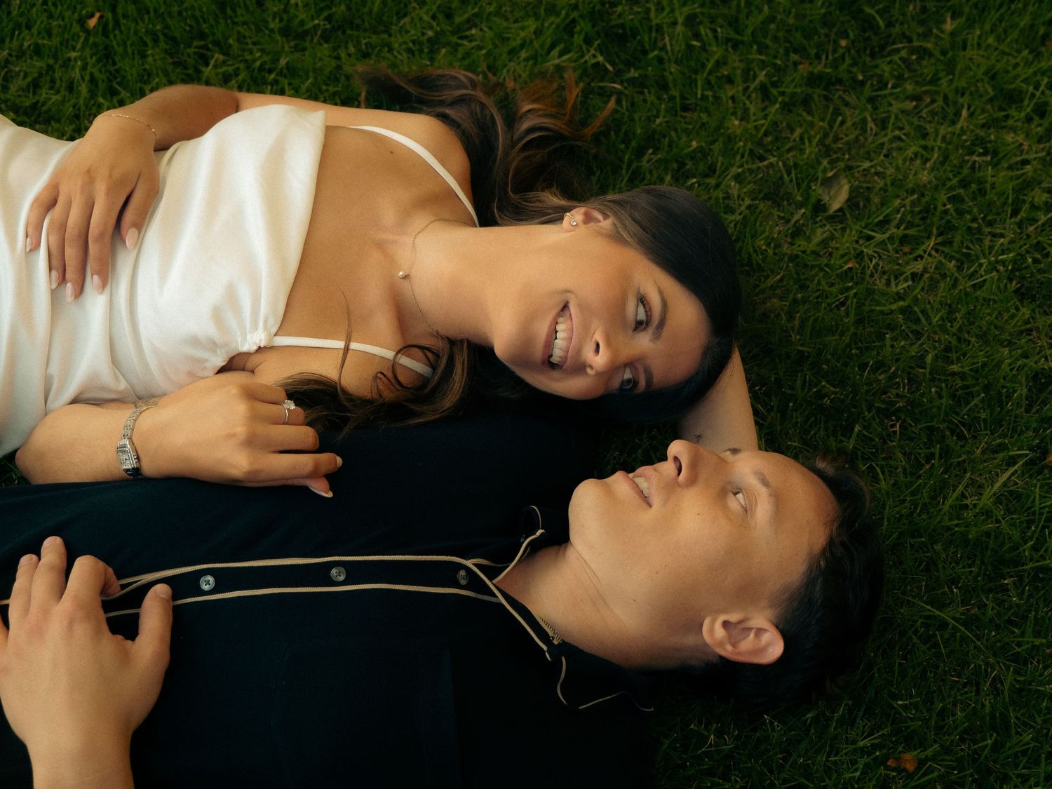 Four images showing someone lying on grass listening to music with earbuds while relaxing outdoors.