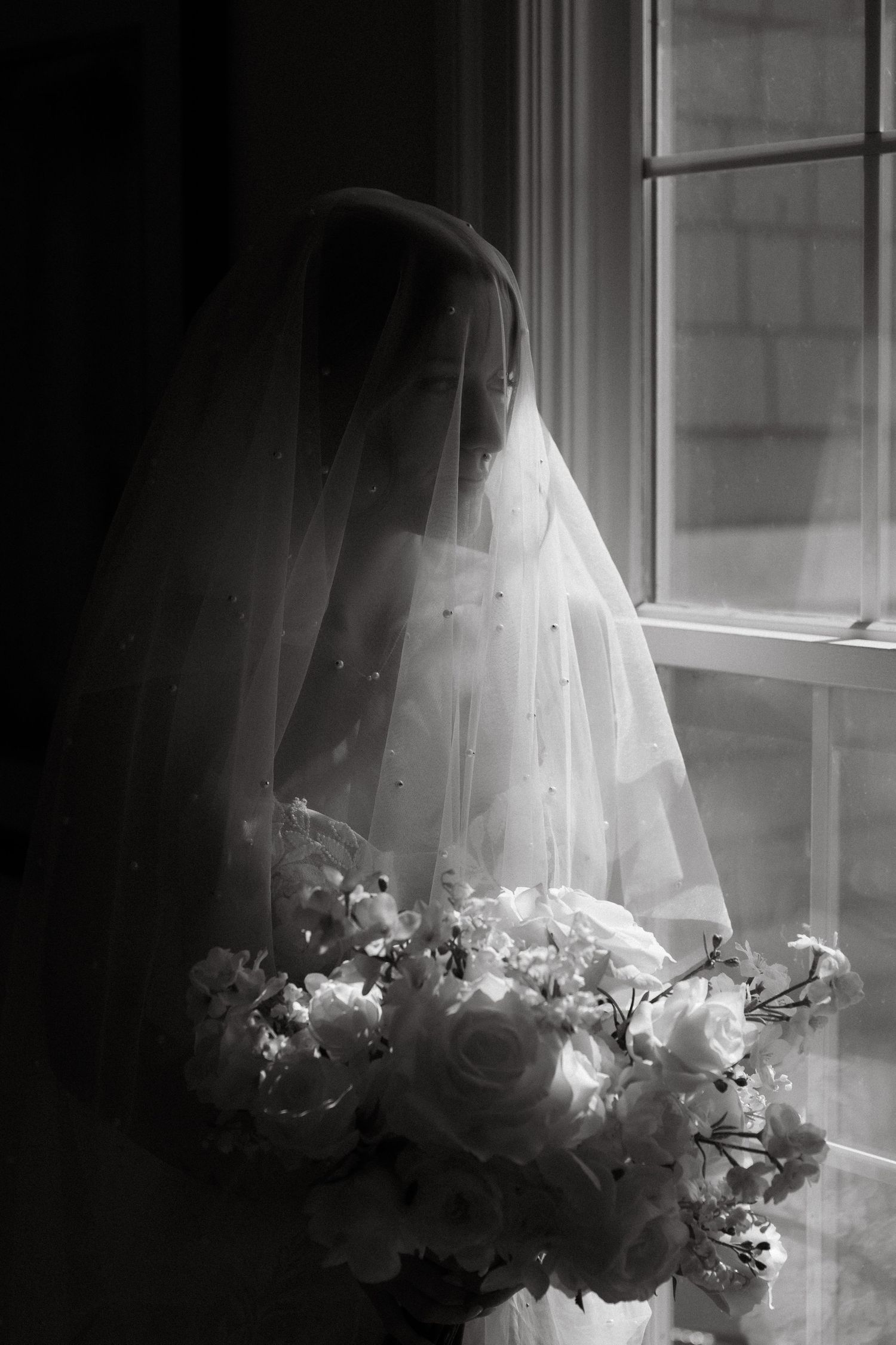 A series of ethereal black and white photographs showing a wedding veil and flowers near a sunlit window.