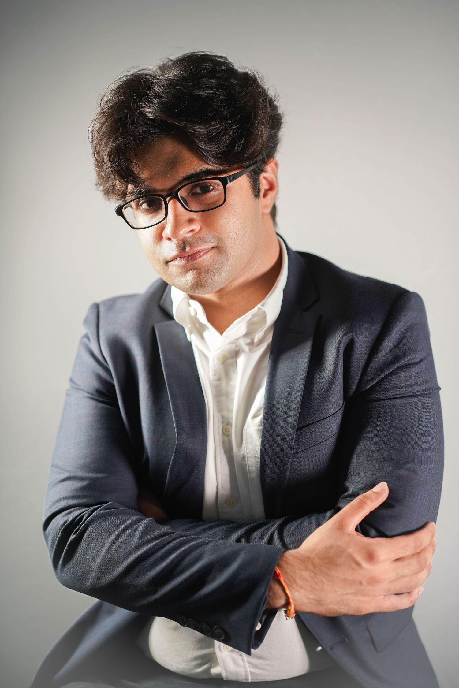 A series of artistic portraits showing a person in a navy blazer and white shirt striking different poses against a light backdrop.