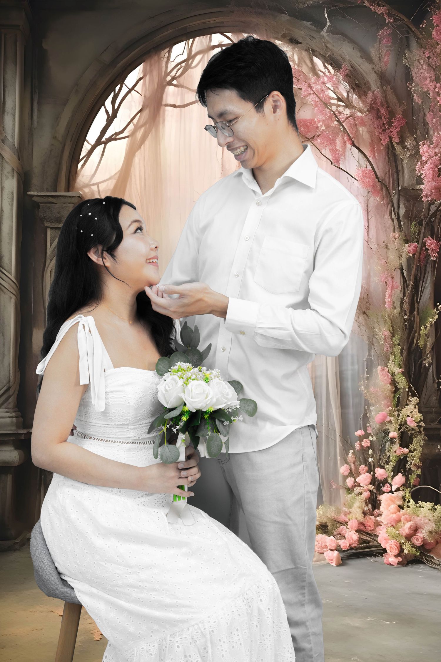 Romantic wedding portrait under an archway with pink floral decorations.