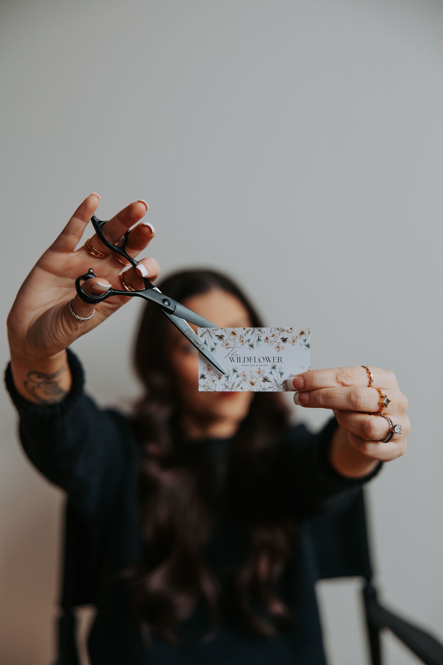 Hands holding scissors cutting a business card with sparkly design.