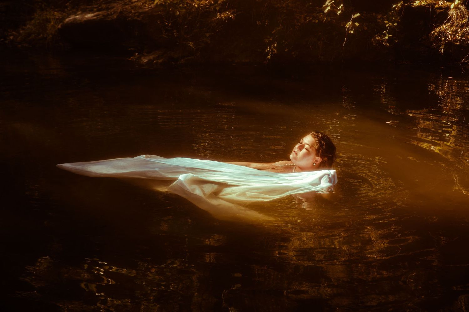 Photo d'une femme allongée dans l'eau lors d'une séance artistique bienveillante en extérieur près de Saint-Étienne
