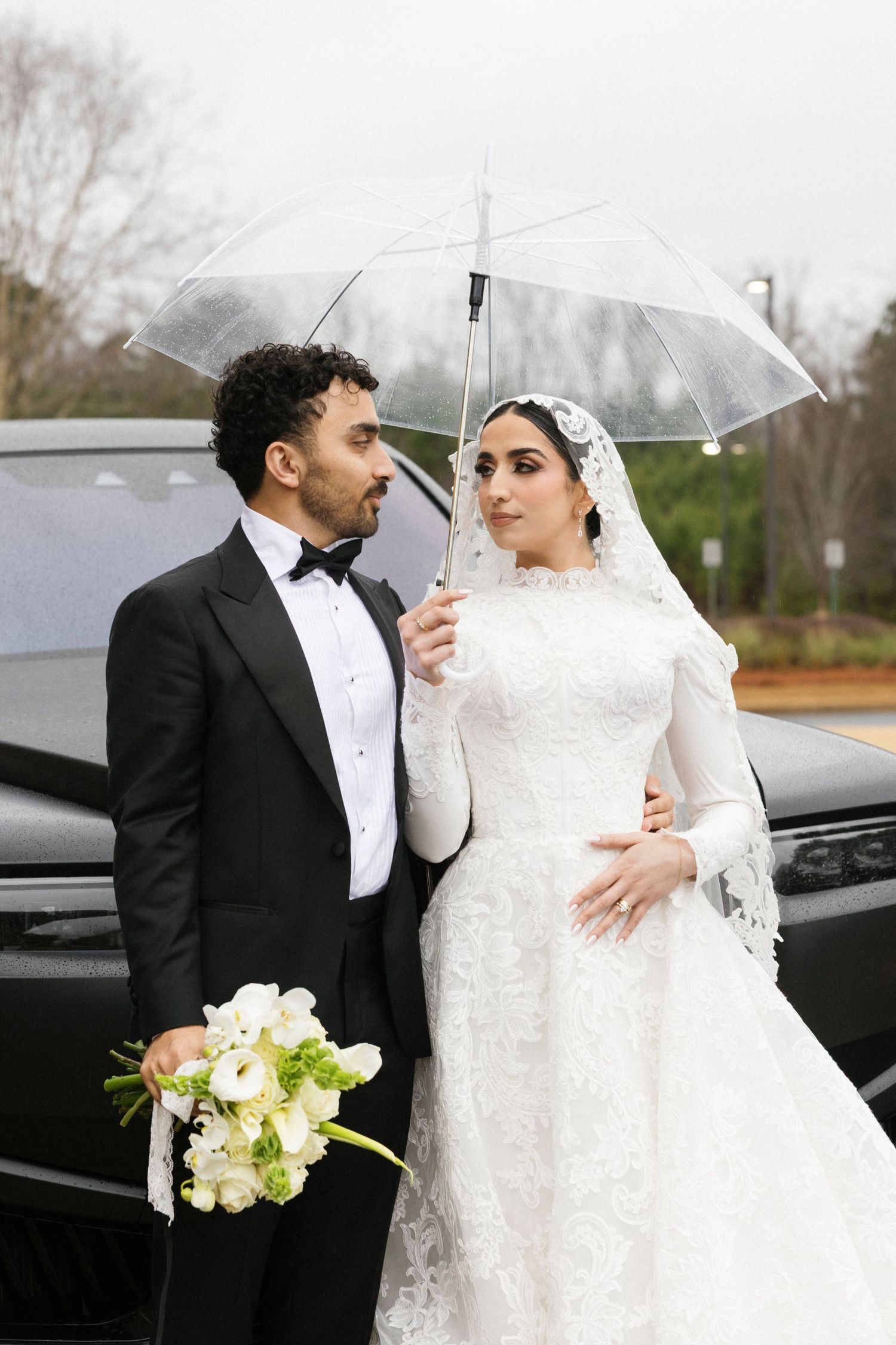 A romantic wedding photoshoot in the rain with a couple sharing intimate moments under clear umbrellas.