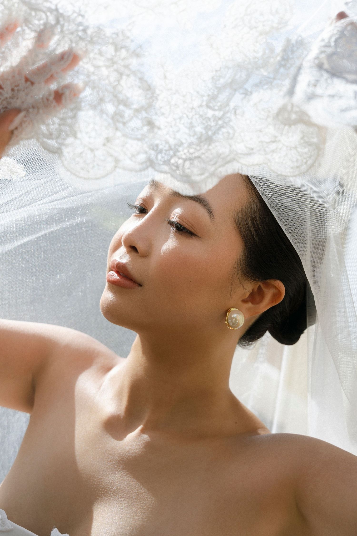 A serene beauty portrait with soft lighting and delicate white tulle fabric creating an ethereal, dreamy atmosphere.