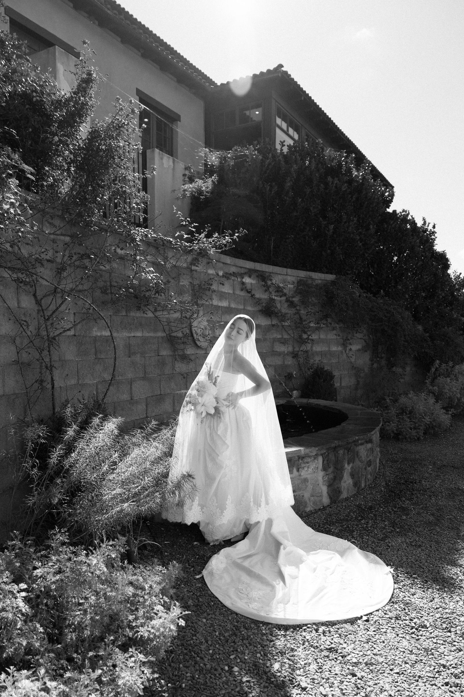 A series of black and white photos showing a figure in a flowing white wedding dress and veil against a stone wall backdrop.