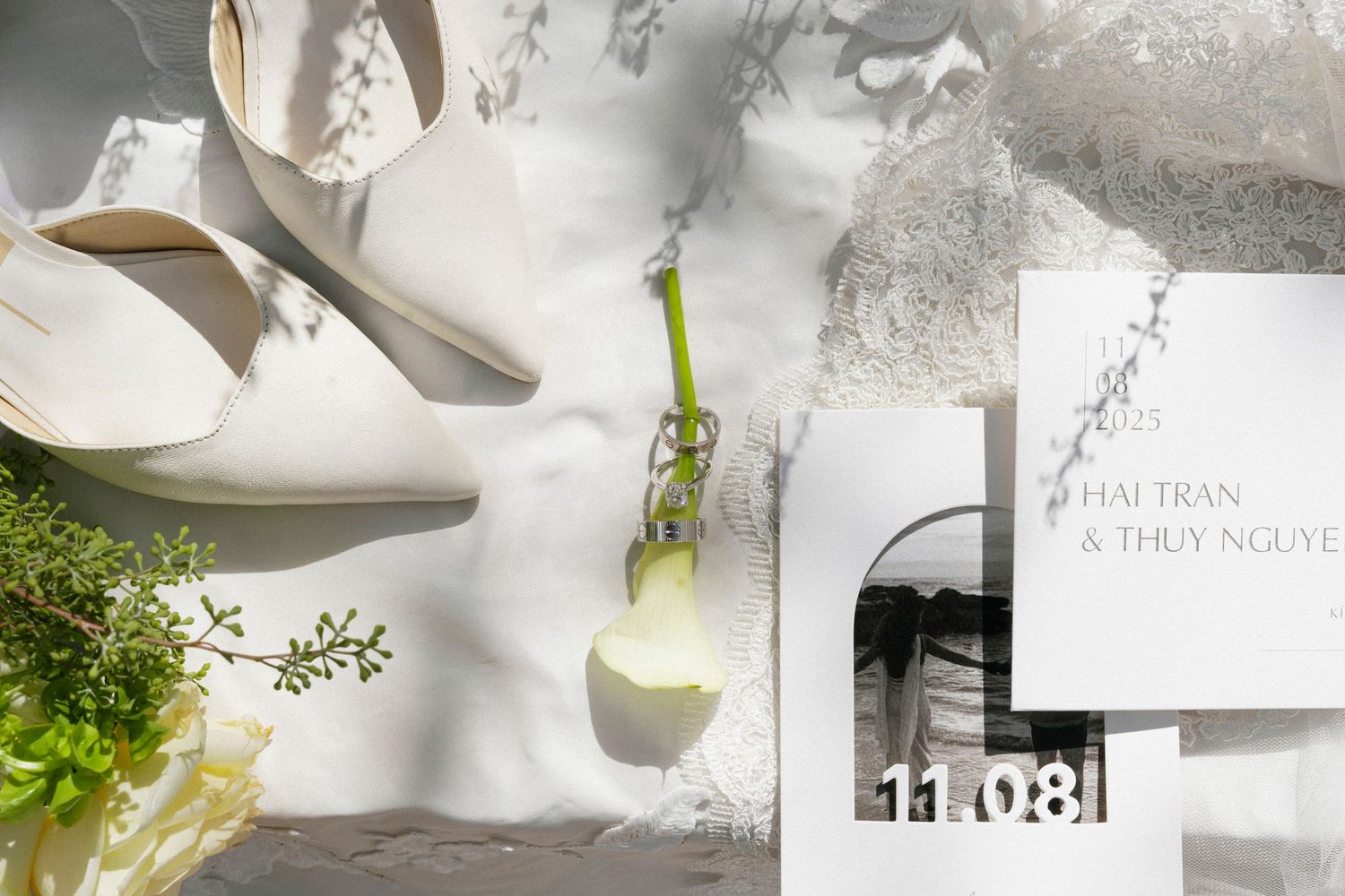 A collection of white ceramic plates and bowls arranged with green herbs and natural decor elements on a light surface.