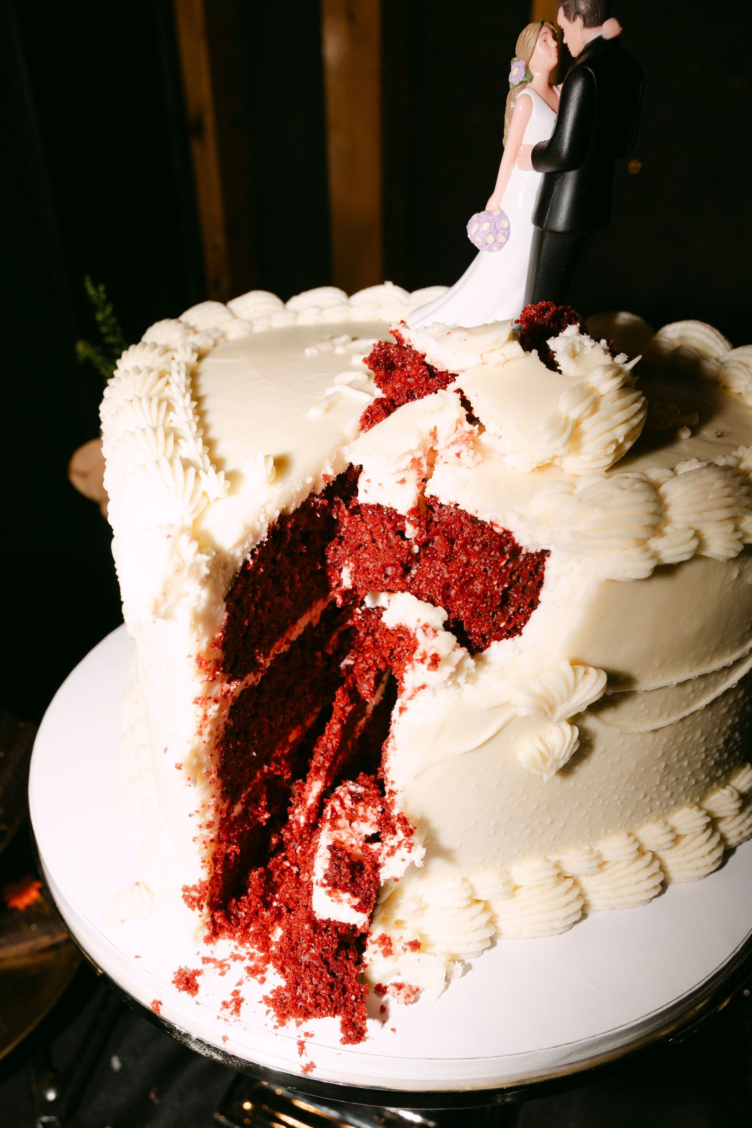A sequence showing a white frosted wedding cake being cut to reveal bright red velvet cake layers inside.