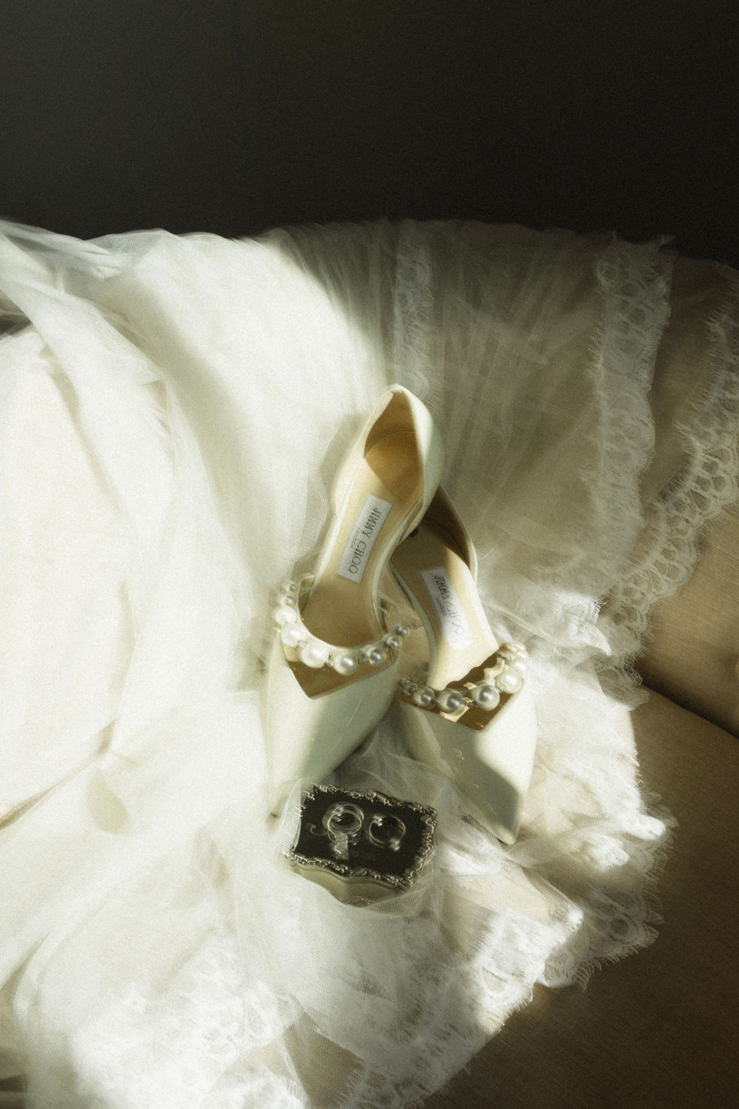 A close-up sequence of elegant white bridal shoes with pearl embellishments against a flowing tulle wedding dress.