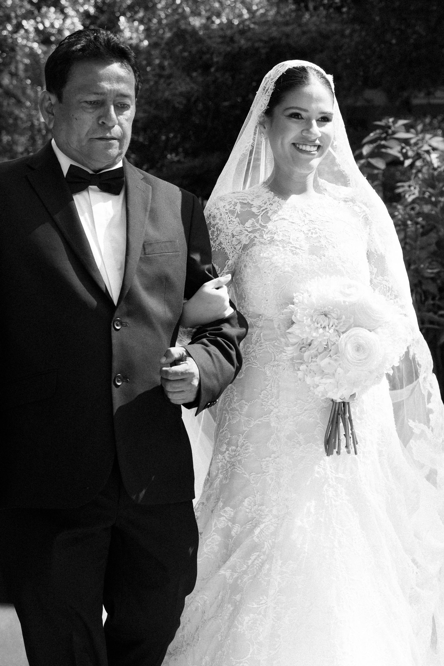 A black and white wedding photo showing a couple on their special day, with the bride in a lace gown and veil.