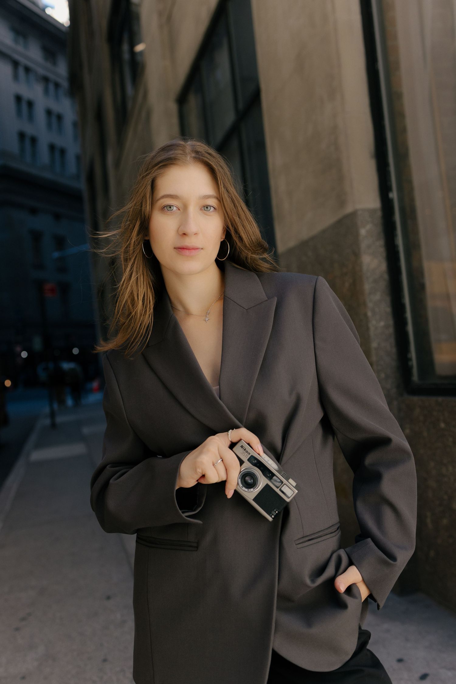 A series of fashion photos showing a person in an oversized dark blazer posing dramatically against an urban backdrop.