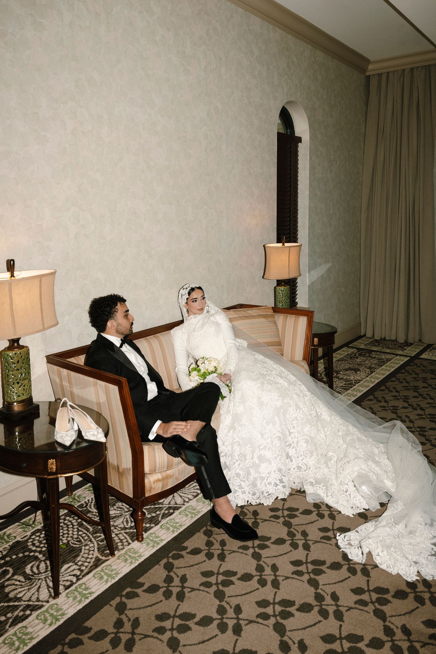 Sequence of wedding couple playfully falling backwards in chairs on patterned hotel room carpet.