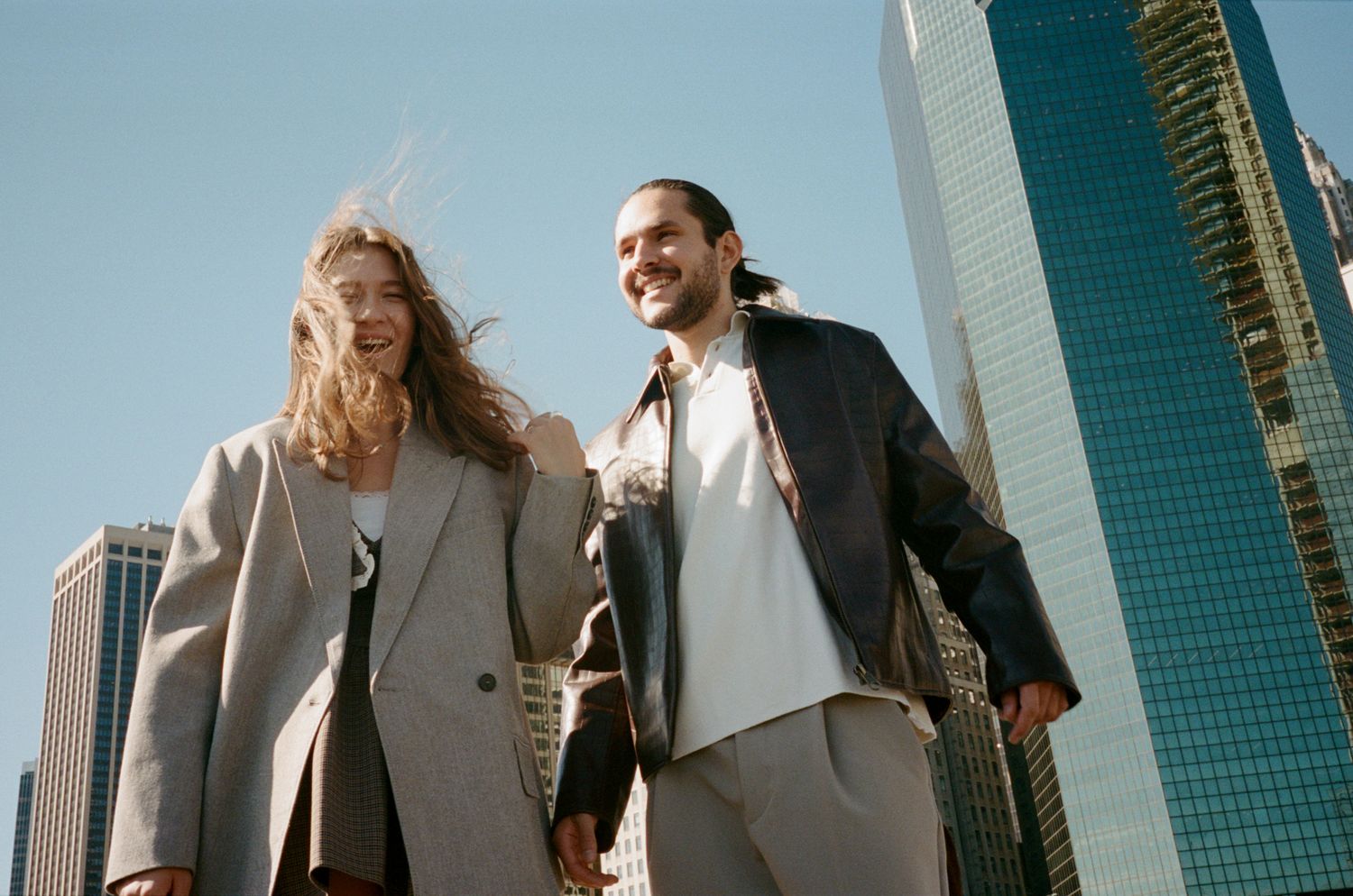 Group of business professionals walking together near modern glass office buildings in an urban setting.