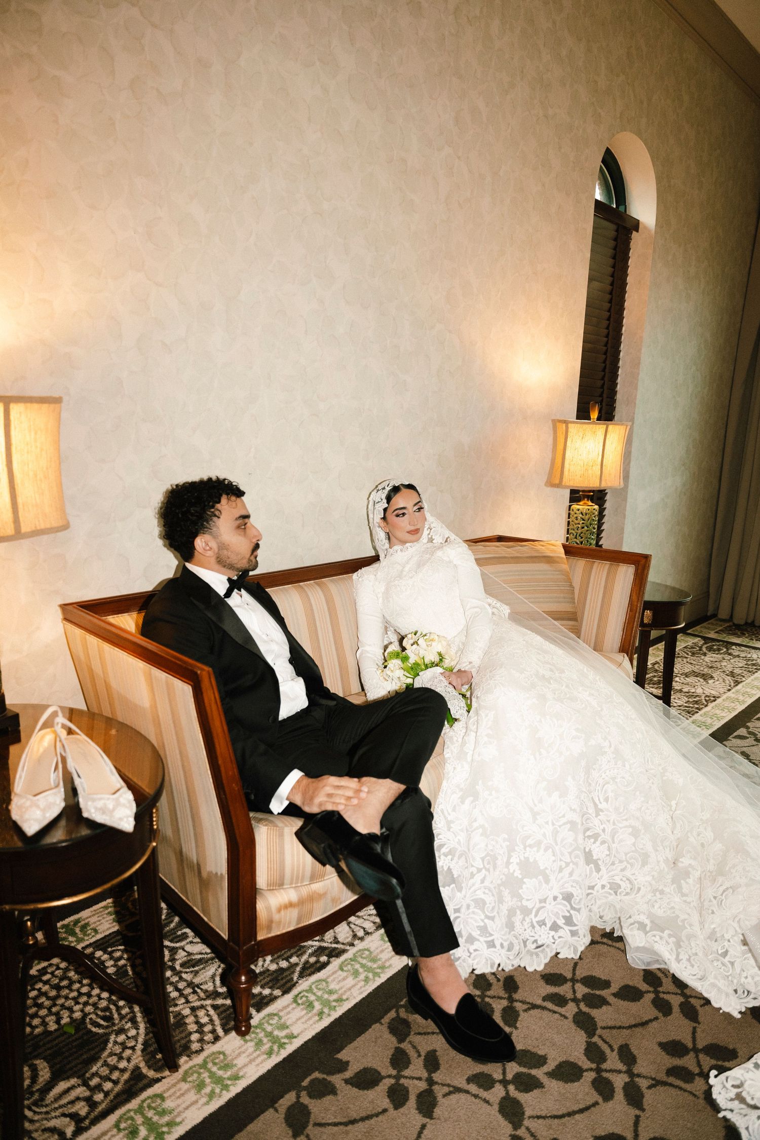 A humorous sequence of wedding photos showing a bride and groom playfully falling off a chair in a hotel room.