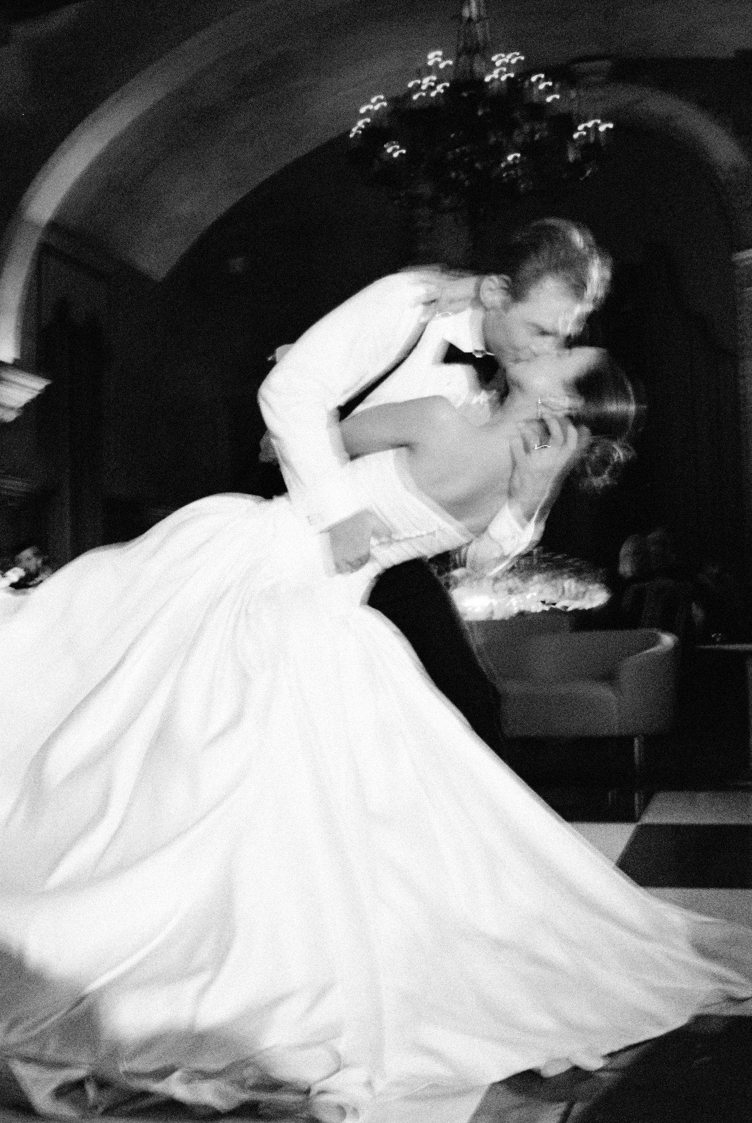 Black and white photo of bride and groom sharing a romantic dip kiss during their first wedding dance.