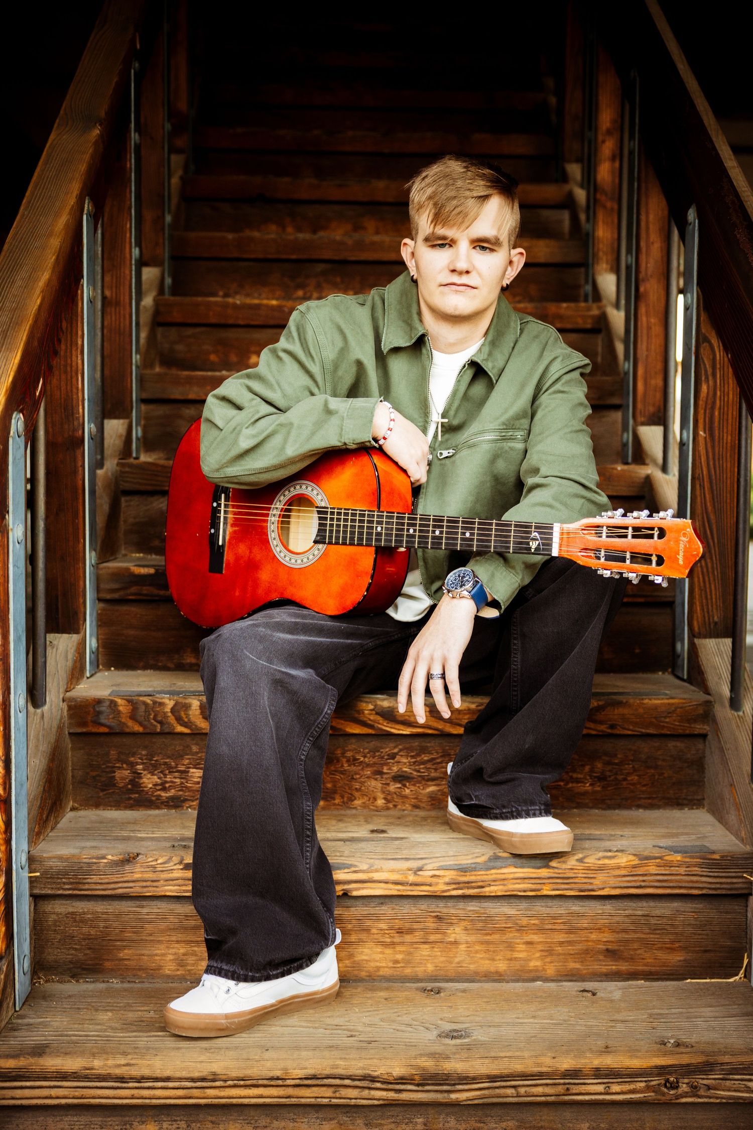Musician sitting on wooden stairs playing an acoustic guitar in a series of progressive shots.